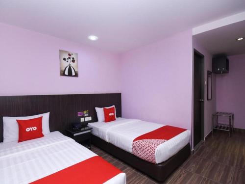 a hotel room with two beds with red and white pillows at Hotel O 98inn in Miri