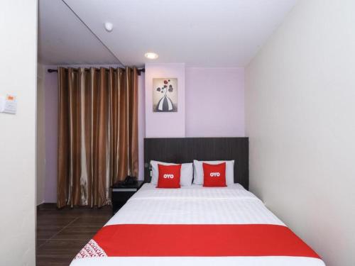 a bedroom with a large bed with red pillows at Hotel O 98inn in Miri