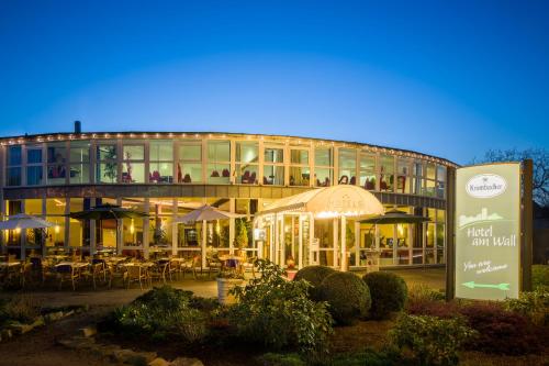 a building with tables and umbrellas in front of it at Hotel am Wall in Soest