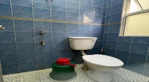 La salle de bains est pourvue de carrelage bleu, de toilettes et d'un tabouret vert. dans l'établissement OYO 90514 Habeeb Lodge Sandakan, à Sandakan