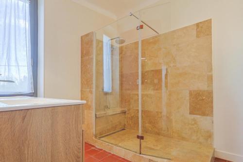 une douche avec une porte vitrée dans une salle de bain dans l'établissement Le Champ des Cigales, à Noves