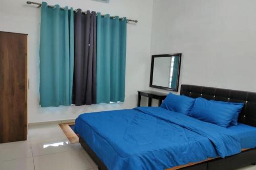 a bedroom with a bed with blue sheets and a mirror at OYO Homes 90611 Homestay D'emas in Melaka