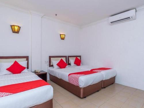 two beds in a room with red pillows at Super OYO 1114 Neo Pegasus Hotel in Segamat