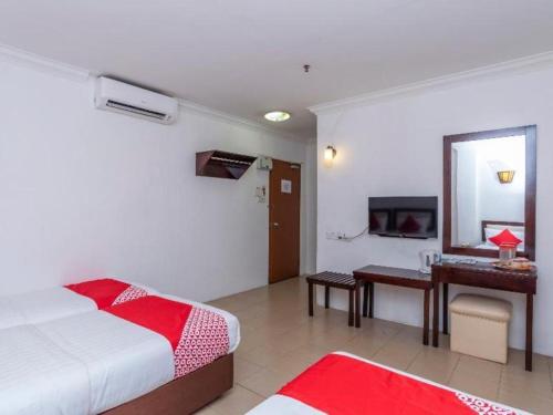 a bedroom with a bed and a desk and a mirror at Super OYO 1114 Neo Pegasus Hotel in Segamat