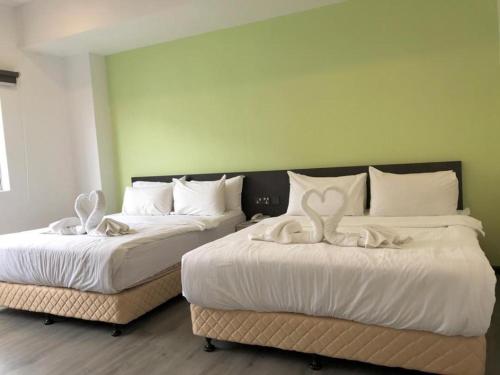 two beds in a room with white sheets at TT Dorf Hotel (Taiping) in Taiping
