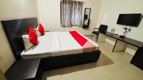 a bedroom with a bed with red pillows and a desk at AP GUEST HOUSE by TWC in Bhubaneshwar