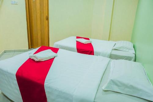 two beds with red and white sheets in a room at KK Inn Hotel Ampang in Kuala Lumpur