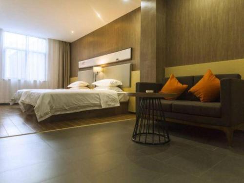 a bedroom with a bed and a couch at Jtour Inn Suizhou Yanhe Avenue in Suizhou