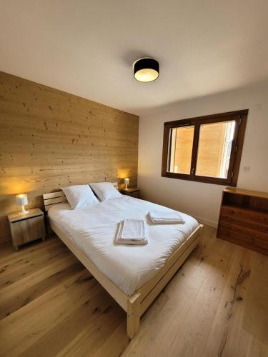 une chambre avec un grand lit avec deux serviettes dessus dans l'établissement Résidence Cottage Alpin - Appartement 4 personnes au calme MAE-0801, aux Gets