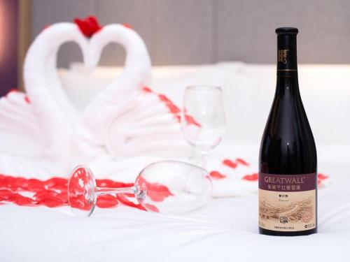 a bottle of wine and glasses on a table with a swan at Lavande Hotel Lu County High-Speed Railway Station Wanhu Daduhui in Luzhou