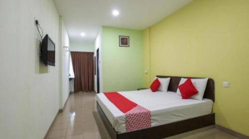 a bedroom with a bed with red and white pillows at HS Hotel Siswa Near UTAR in Kampar
