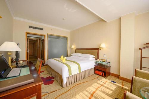 a bedroom with a bed and a desk with a laptop at Quanzhou Overseas Chinese Hotel in Quanzhou