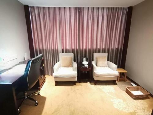 a hotel room with two chairs and a bed at Quanzhou Overseas Chinese Hotel in Quanzhou