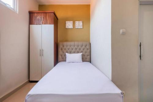 a bedroom with a white bed and a cabinet at OYO Living 1877 Side Corner in Kanggraksan
