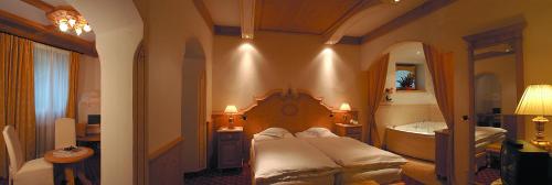 a bedroom with a bed and a tub in a room at Hotel Al Forte in Arabba