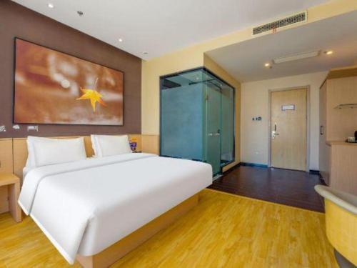 a bedroom with a large white bed and a bathroom at IU Hotel Taiyuan Changfeng West Street The Mixc in Taiyuan