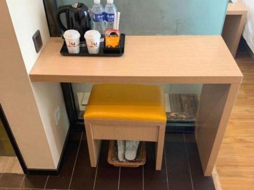 a table with a yellow stool and drinks on it at IU Hotel Taiyuan Changfeng West Street The Mixc in Taiyuan