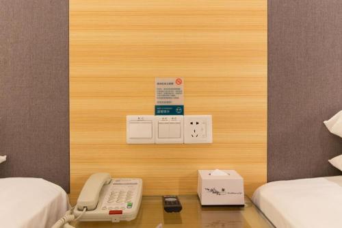 Cette chambre comprend deux lits et un téléphone sur une table. dans l'établissement City Comfort Inn Dongguan Nancheng Tian'an Digital City, à Dongguan