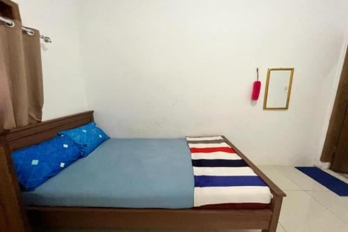 a small bedroom with a bed with a blue bedspread at OYO 93784 Kost Bu Eli Syariah in Malang