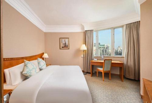 a hotel room with a large bed and a desk at Haihua Hotel Hangzhou in Hangzhou