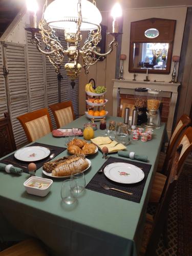 a table with a green table cloth with food on it at Chambre d'hôtes Juste-Confortable in Fleurey-lès-Lavoncourt