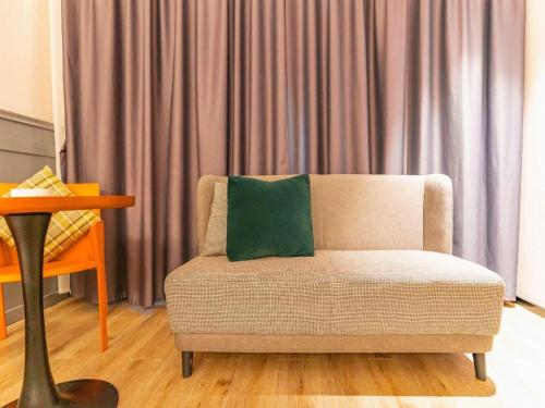 a living room with a couch with a green pillow at City Comfort Premier Hotel Xiaogan Anlu Railway Station Dongda Times Square in Xiaogan