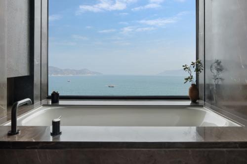 a bath tub with a window with a view of the ocean at Alila Dong'Ao Island Zhuhai in Zhuhai