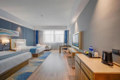 a hotel room with two beds and a television at The Long Red Hotel Daye Huangshi in Huangshi