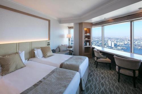 a hotel room with two beds and a desk at Yokohama Royal Park Hotel in Yokohama