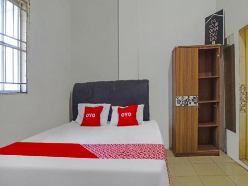 a bedroom with a bed with two red pillows at OYO 92403 Gatsu Homestay in Medan