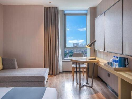 a hotel room with a bed and a table and a window at Echarm Hotel Taizhou International Convention and Exhibition Center 