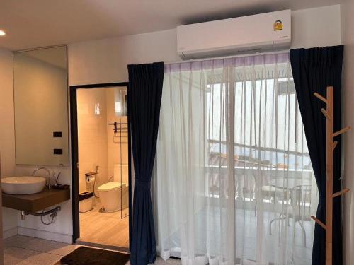 a bathroom with a window and a sink and a toilet at Calm Kamala Phuket in Kamala Beach