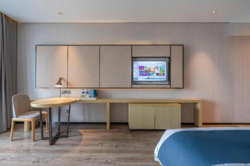 a room with a bed and a desk and a tv at Echarm Hotel Taizhou International Convention and Exhibition Center 