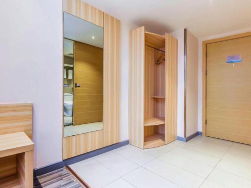 Elle comprend un dressing avec des portes en bois et un miroir. dans l'établissement City Comfort Inn Chongqing Southwest University Beibei Metro Station, à Huangjuezhen