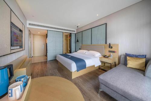 a hotel room with a bed and a couch at Echarm Hotel Taizhou International Convention and Exhibition Center 