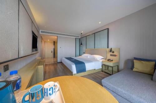 a hotel room with a bed and a couch at Echarm Hotel Taizhou International Convention and Exhibition Center 