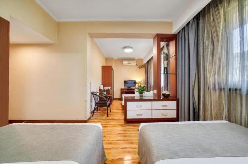 a hotel room with two beds and a desk at Hangzhou Bokai Westlake Hotel in Hangzhou