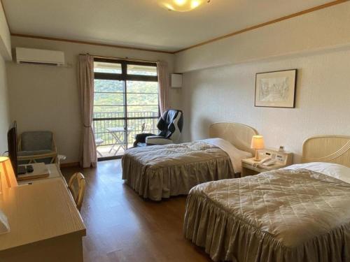 a hotel room with two beds and a window at Hotel Bellreef Otsuki in Otsuki
