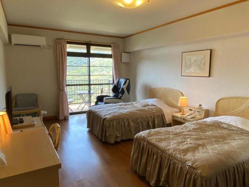 a hotel room with two beds and a window at Hotel Bellreef Otsuki in Otsuki