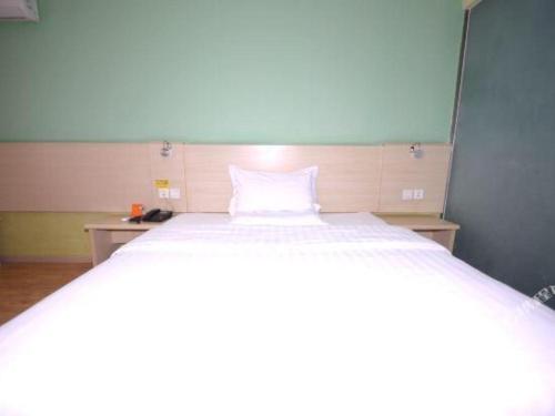 a bedroom with a large bed with a white pillow at 7 Days Inn Baoding Railway Station in Baoding