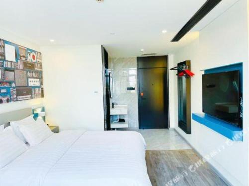 a bedroom with a white bed and a television at 7 Days Inn Baoding Railway Station in Baoding