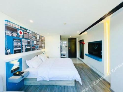 a bedroom with a large white bed and a television at 7 Days Inn Baoding Railway Station in Baoding