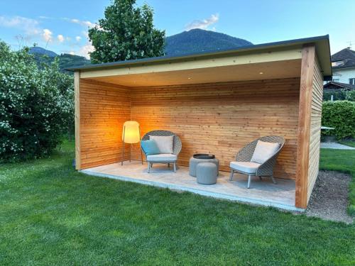 a wooden shed with two chairs and a grill at Haus Wiesenstein in Lana