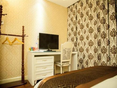 a bedroom with a bed and a desk with a television at GreenTree Alliance Anhui Hefei South Passenger Station South High Speed Railway Station Hotel in Hefei