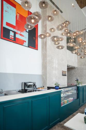 a kitchen with blue cabinets and silver pendant lights at AR Suites KLJ Square in Gurgaon