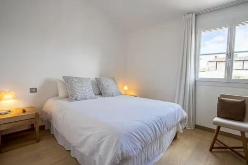 a bedroom with a white bed and a desk and a window at Balandrine in Grimaud
