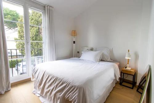 a white bed in a room with a large window at Balandrine in Grimaud