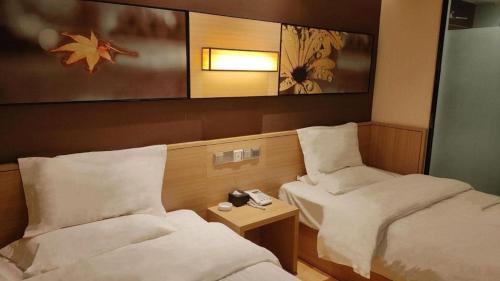 a room with two beds and a phone on a table at 7 Days Inn Zhangjiakou Chongli Yuxing Road in Zhangjiakou