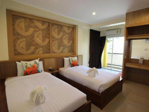 a hotel room with two beds and a window at Mon Muang Hotel in Chiang Mai