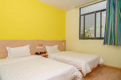 two beds in a room with yellow walls and a window at 7 Days Inn Suzhou Wangting Pearl Commercial Plaza in Suzhou
